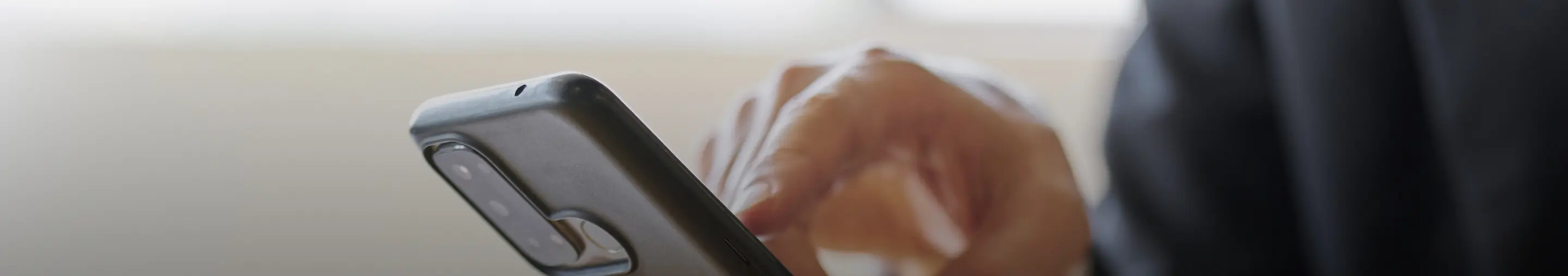 ビジネススーツ姿の人物がスマホ画面をタップしている場面