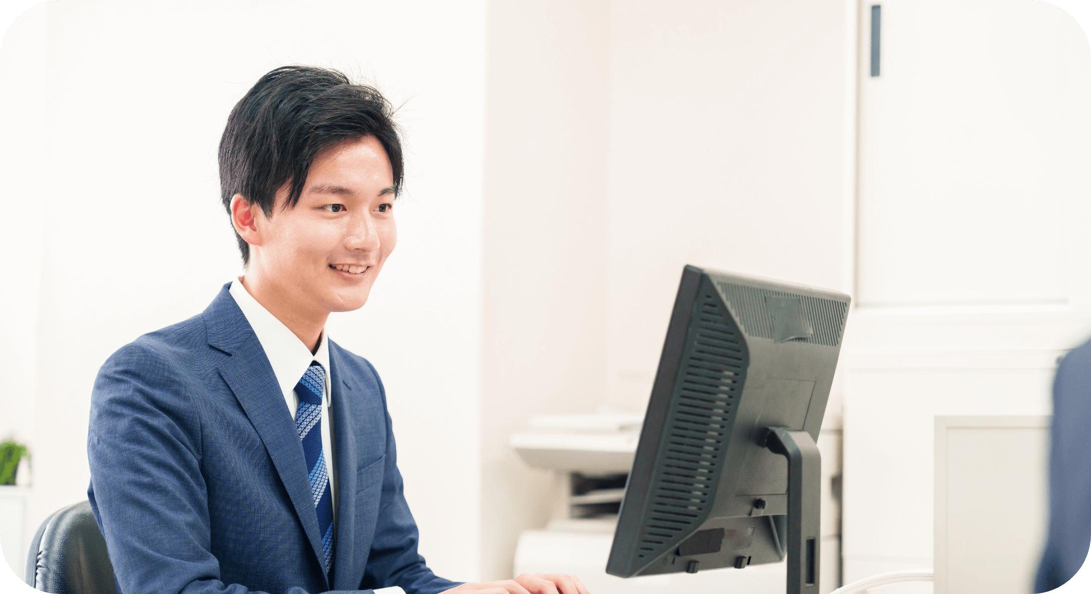 明るい室内でデスクワークに集中するスーツ姿の男性社員